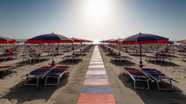 Ombrelloni e lettini vuoti su una spiaggia al tramonto.