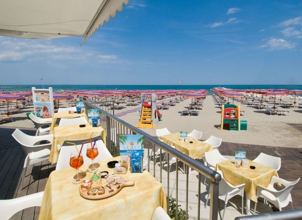 Tavoli all'aperto con bevande su una terrazza vista mare.