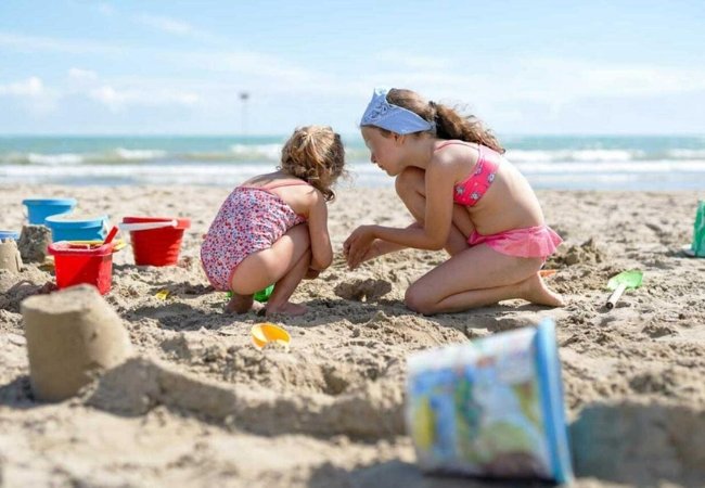 Bambine giocano con la sabbia su una spiaggia.