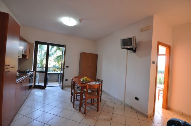 Cucina moderna con tavolo da pranzo, sedie e televisore.