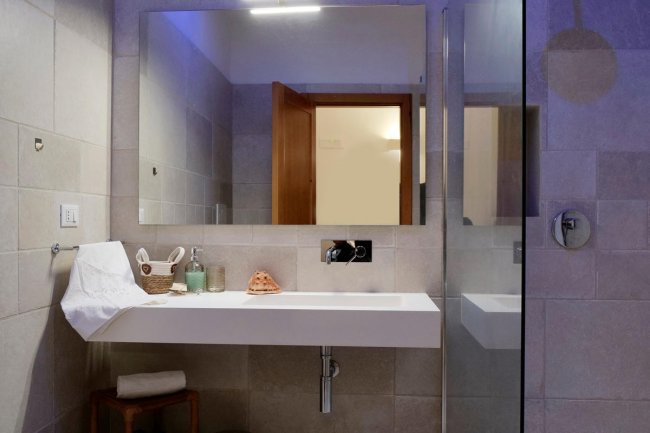 Un bagno con lavabo moderno, ampio specchio e accessori da toilette.