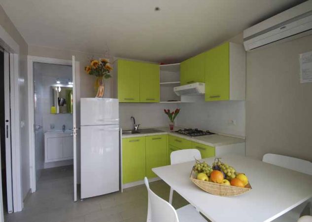 Cucina moderna con mobili verdi e frutta sul tavolo.