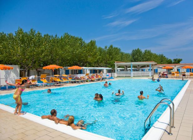 Piscina affollata con sdraio e ombrelloni arancioni.