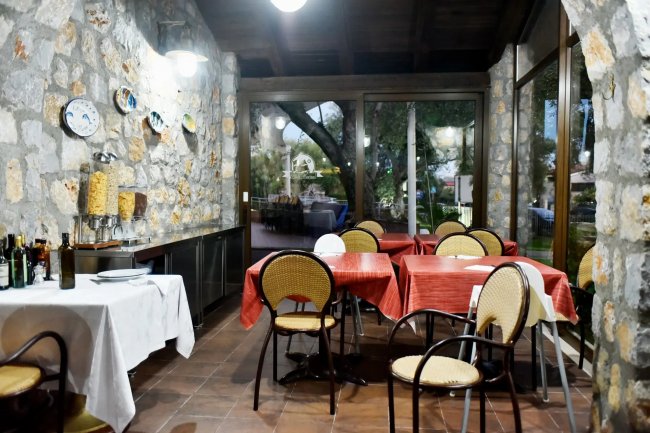 Sala da pranzo rustica con tavoli apparecchiati.
