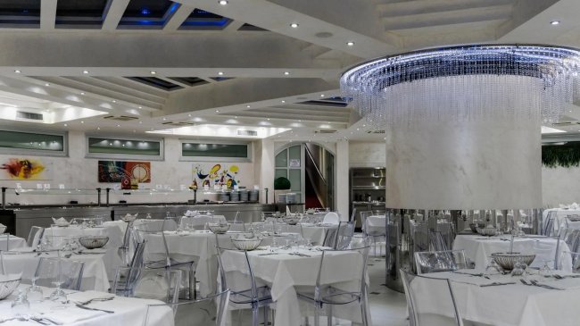 Ristorante elegante con tavoli bianchi e lampadario moderno.