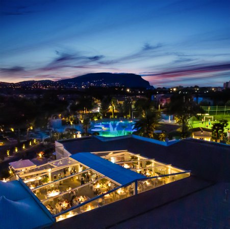 Veduta serale di una città con un ristorante illuminato e un cielo al tramonto.
