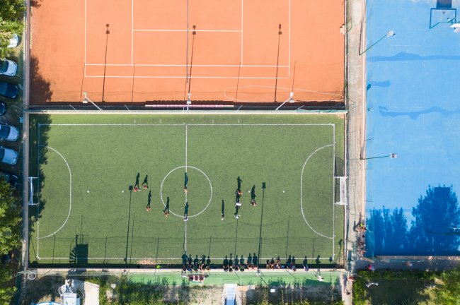 Campo sportivo con calciatori in allenamento, visto dall'alto. Campi adiacenti.