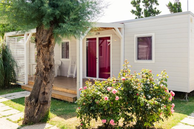 Casa mobile con veranda fiorita e giardino verde.
