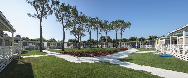 Bungalow circondati da prati verdi e alberi alti.